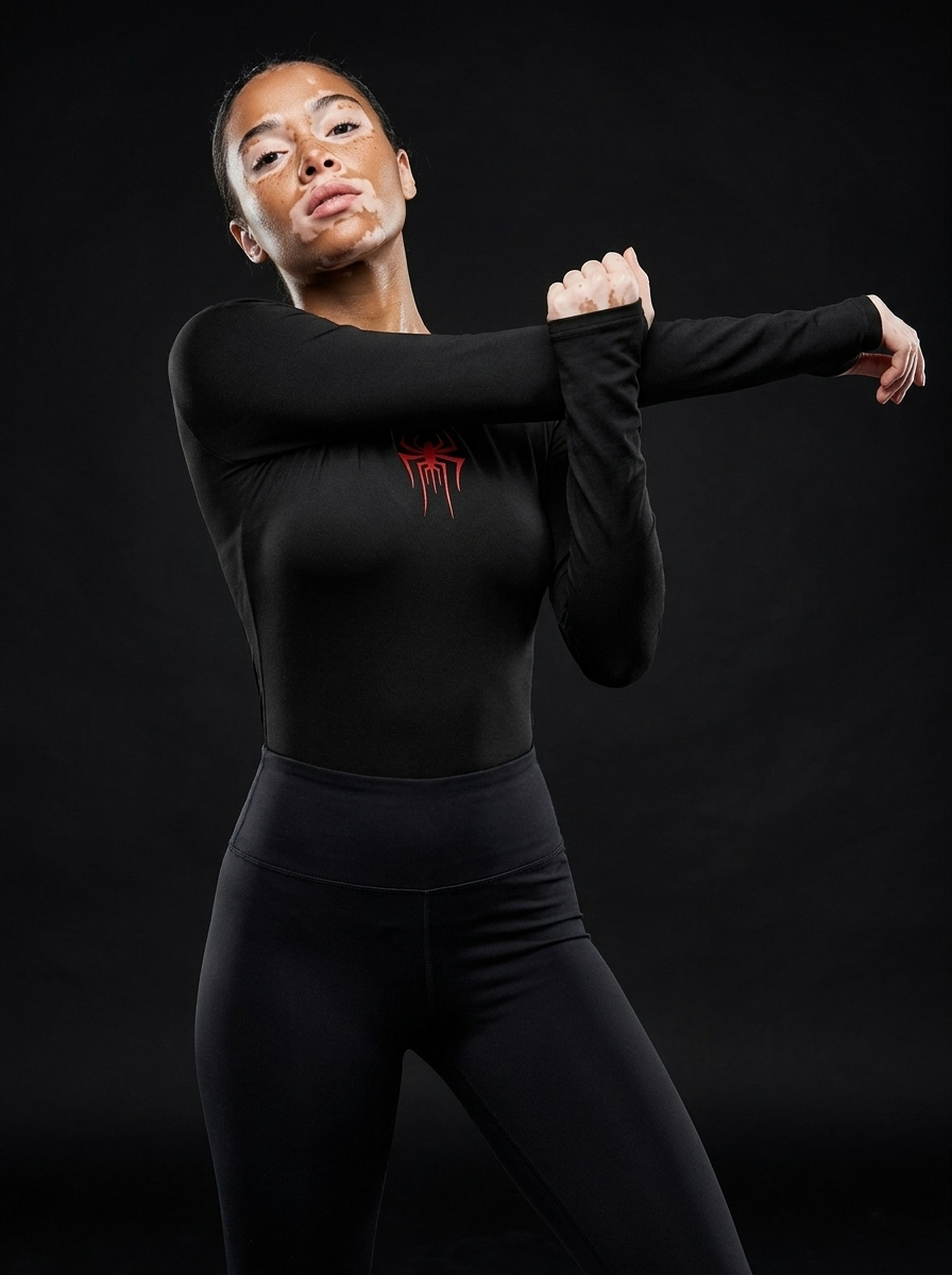 Athletic female model with vitiligo wearing Vagabane Arachnita spider print crop top — studio campaign shot